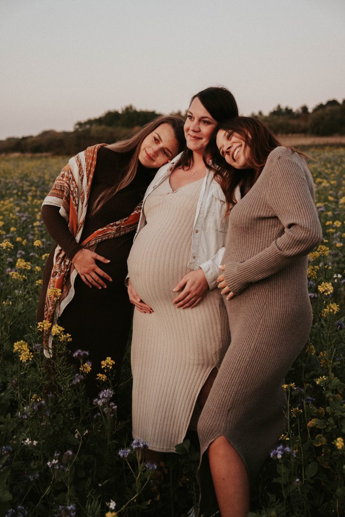 Femme enceinte de profil en pull beige les mains sur le ventre, séance photo maternité