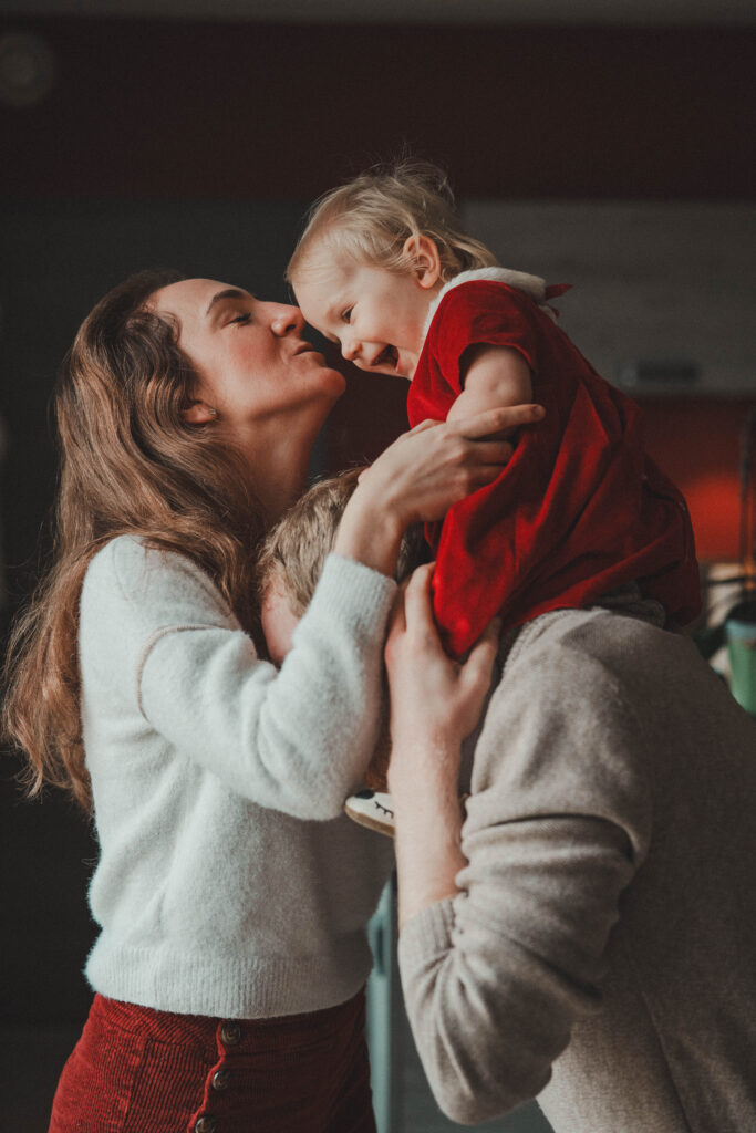 Mère embrassant tendrement son enfant habillé en rouge, séance photo de famille